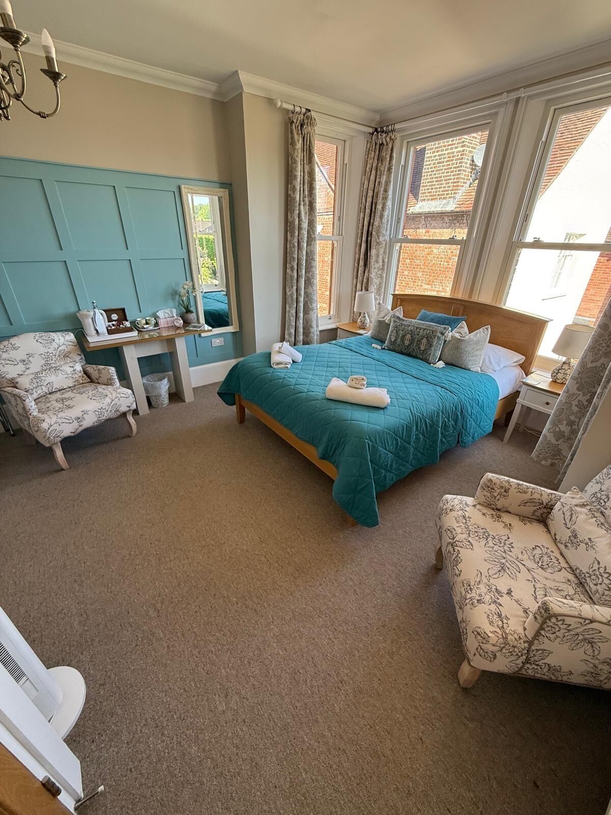 A bedroom with a bed, two chairs, a desk, and a mirror.