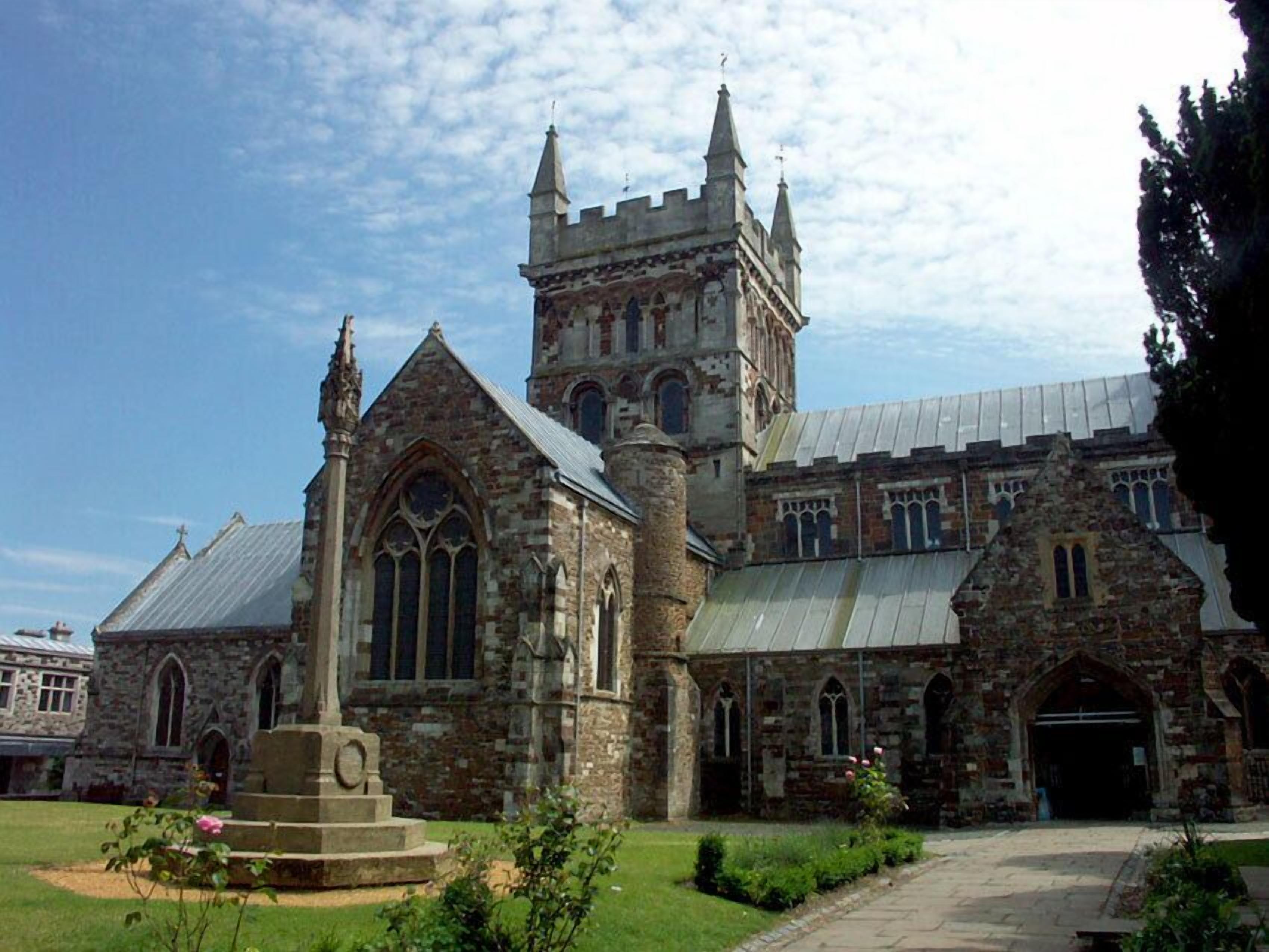 A historic stone building with a prominent tower, arched windows, and a central courtyard with a statue.