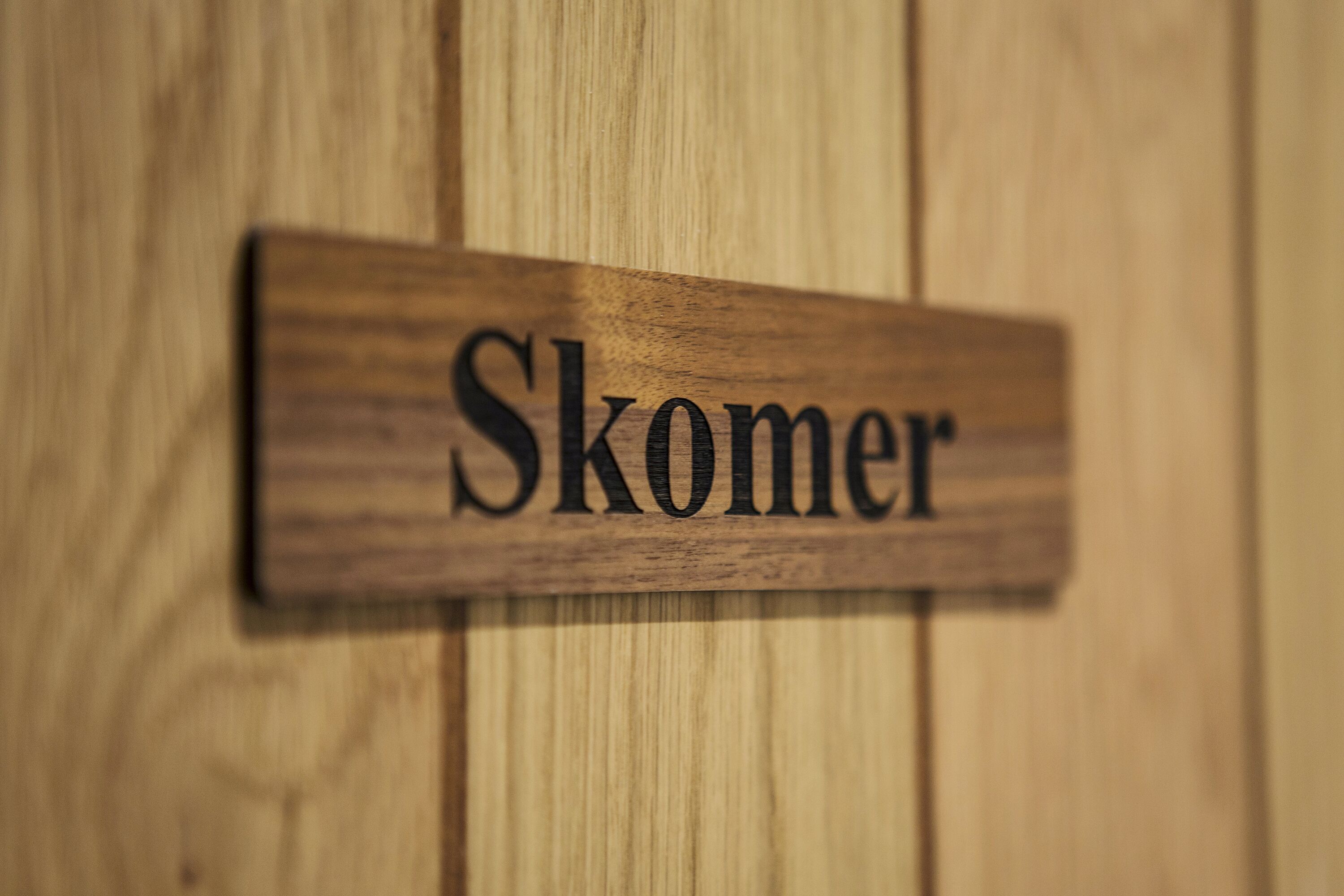 A wooden nameplate with the word "Skomer" on it.
