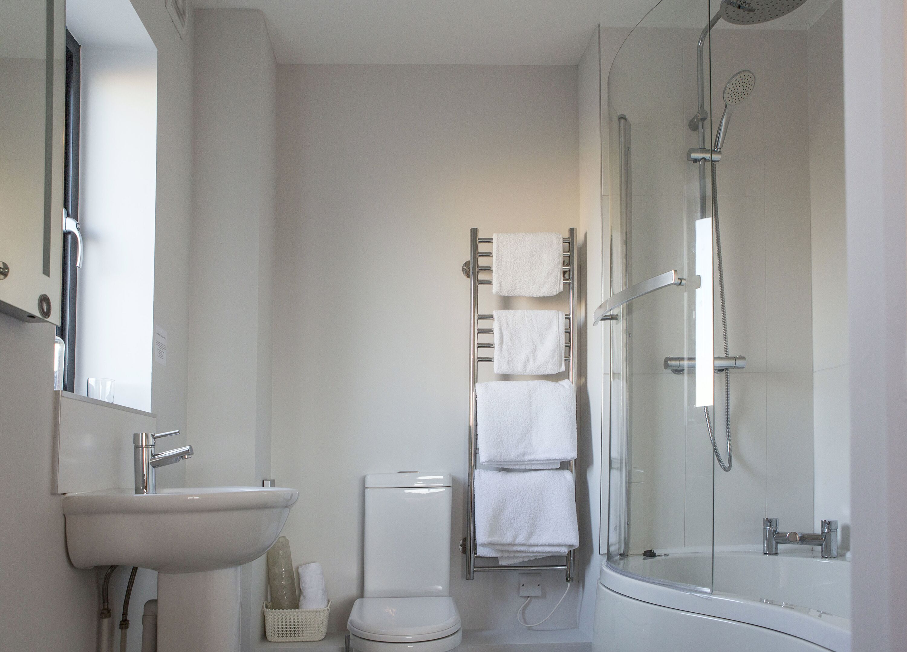 Un baño moderno con lavamanos, inodoro y ducha con mampara de vidrio.