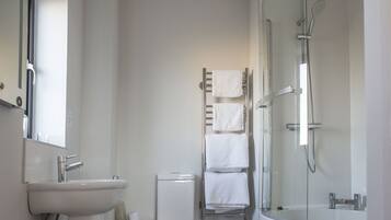 Un baño moderno con lavamanos, inodoro y ducha con mampara de vidrio.