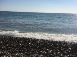 Una playa pedregosa con olas mansas lamiendo la orilla.