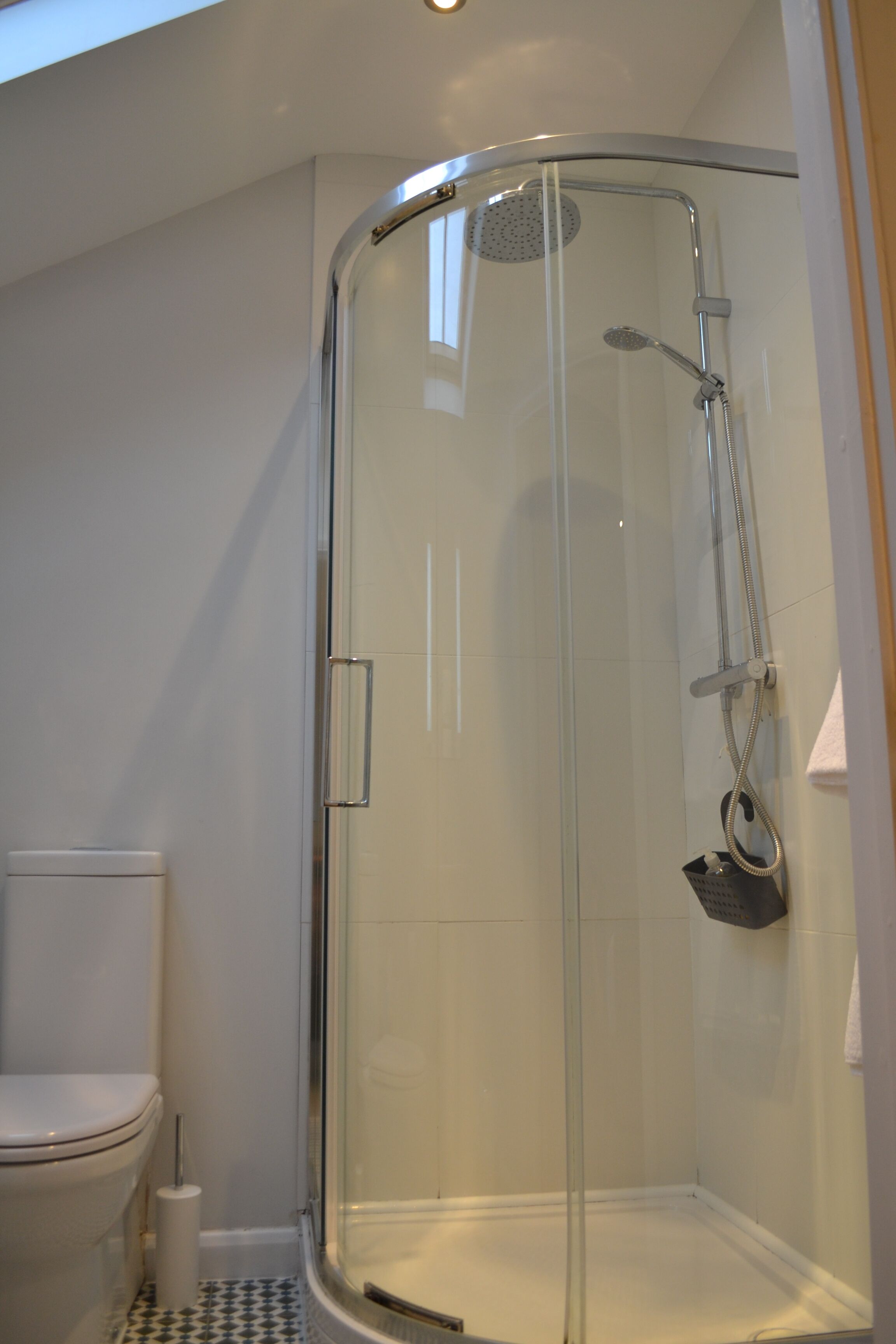 A modern bathroom with a glass-enclosed shower, a toilet, and a bidet.