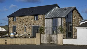 A stone building with a sloped roof, large windows, and a wooden fence. - Victoria Inn Brewhouse B&B (Haverfordwest)