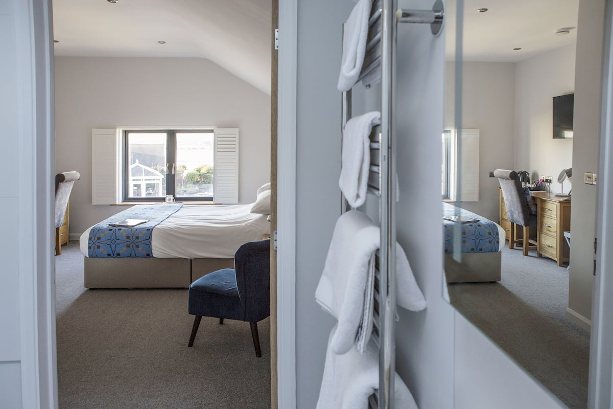Une chambre à coucher avec un lit, une chaise, un bureau et un miroir.