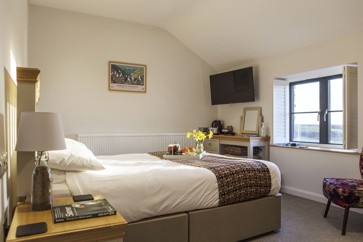 Une chambre d’hôtel avec un lit, une table de chevet, une lampe et une fenêtre donnant sur un paysage agréable.