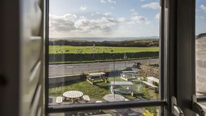 A view from inside a building, looking out to a green field with sheep, picnic tables, and a road. - Victoria Inn Brewhouse B&B (Haverfordwest)