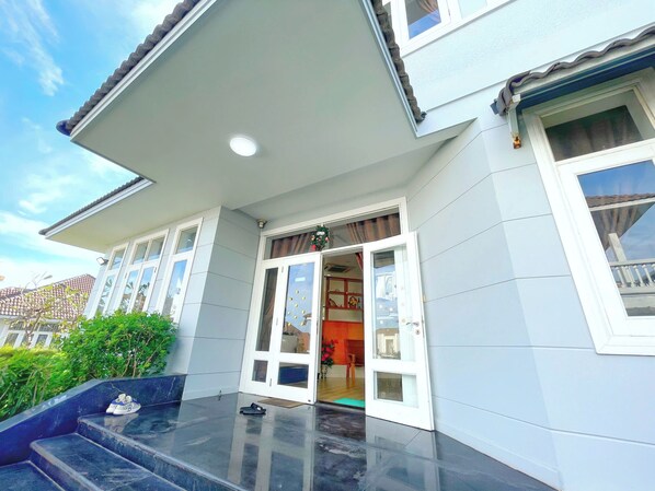 A house with a front porch, a door with glass panels, and a small step leading up to the entrance.