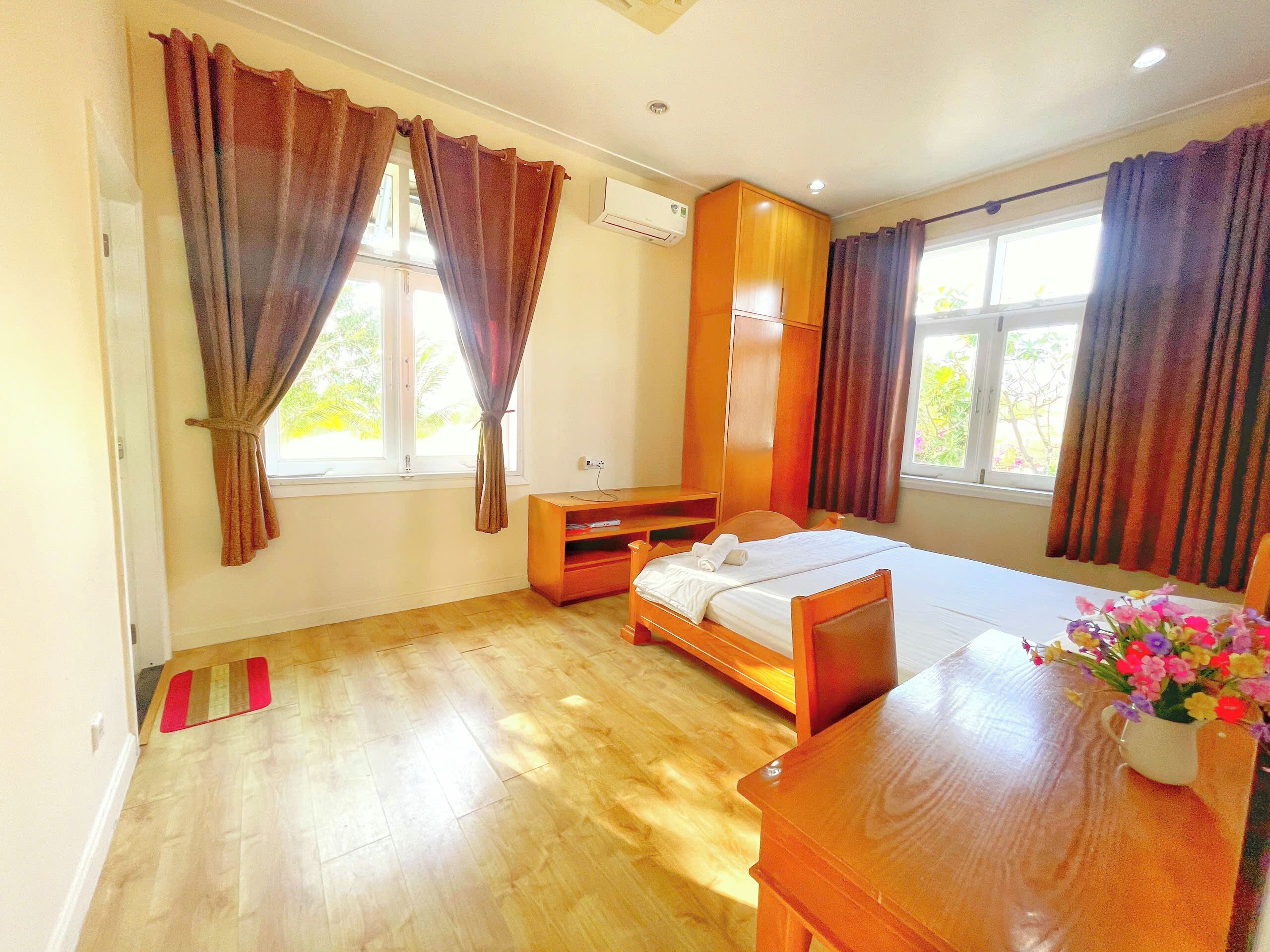 A room with a bed, a desk, a wardrobe, and a window with curtains.