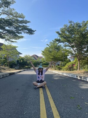 A person sitting on a road with trees and houses in the background. - Sealink Villas Phan Thiet Mui Ne (Phan Thiet)