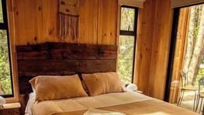 Una stanza in legno con un letto, una finestra e una sedia.