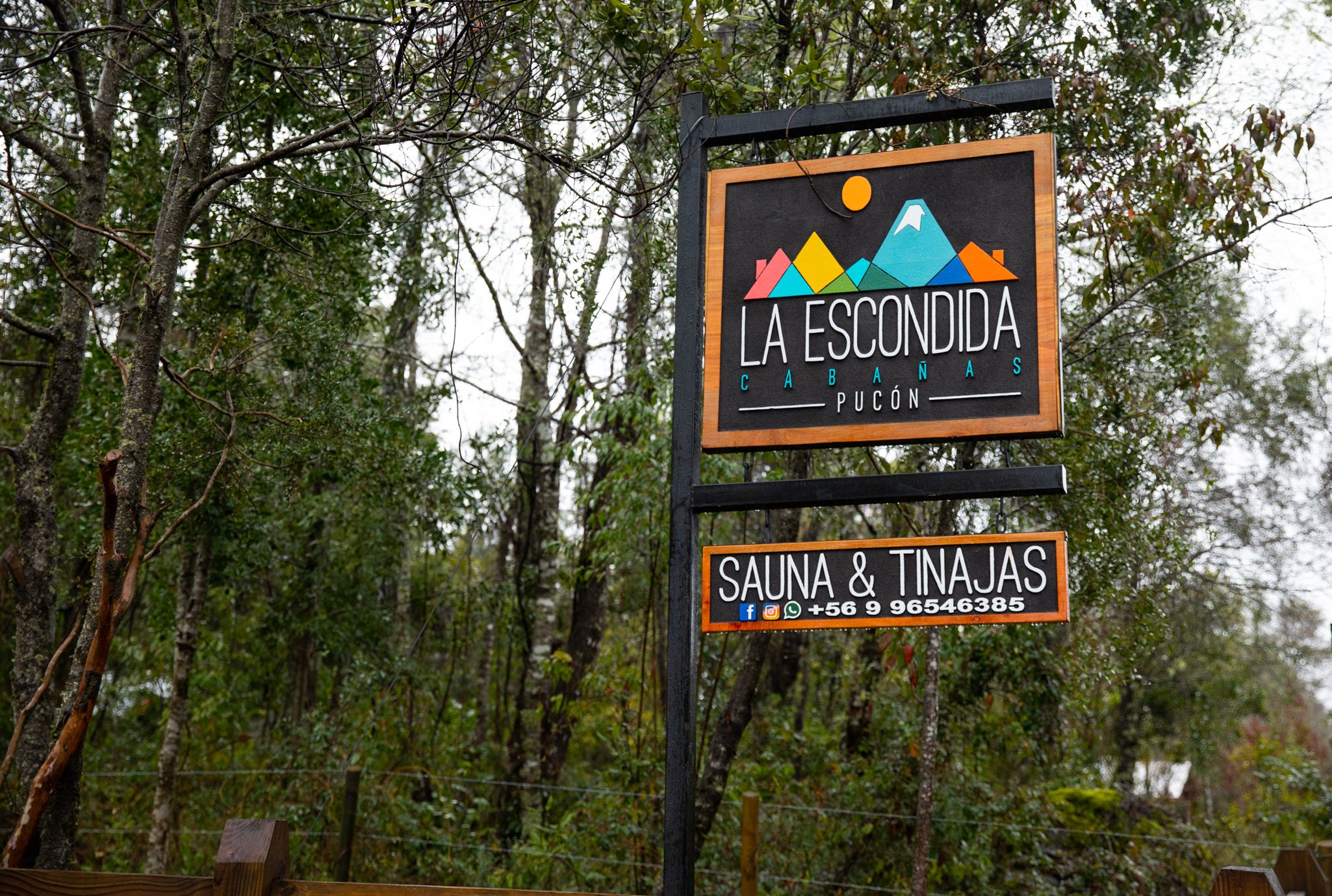 A sign for 'La Escondida Cabanas Pucon' with contact information for 'Sauna & Tinas'.
