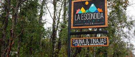 A sign for 'La Escondida Cabanas Pucon' with contact information for 'Sauna & Tinas'.