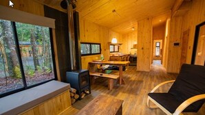 Un interno accogliente di una baita, con finiture in legno, una panca vicino alla finestra, un tavolo e una sedia nera.