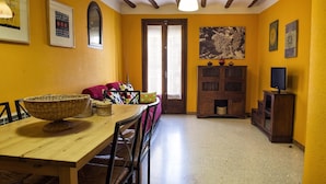 A dining area with a wooden table, wicker baskets, and a sofa with colorful cushions. - Lo Raconet de la Plaça (Calaceite)