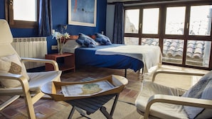A bedroom with a bed, a chair, a table with a map, and a window with a view of the outside. - Lo Raconet de la Plaça (Calaceite)