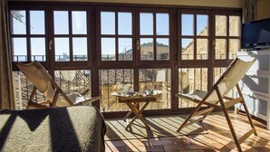A balcony with two folding chairs, a small table with cups and a plate, and a TV on the wall. - Lo Raconet de la Plaça (Calaceite)