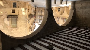 A view of a stone staircase with a curved railing, leading to a balcony with a metal gate. - Lo Raconet de la Plaça (Calaceite)