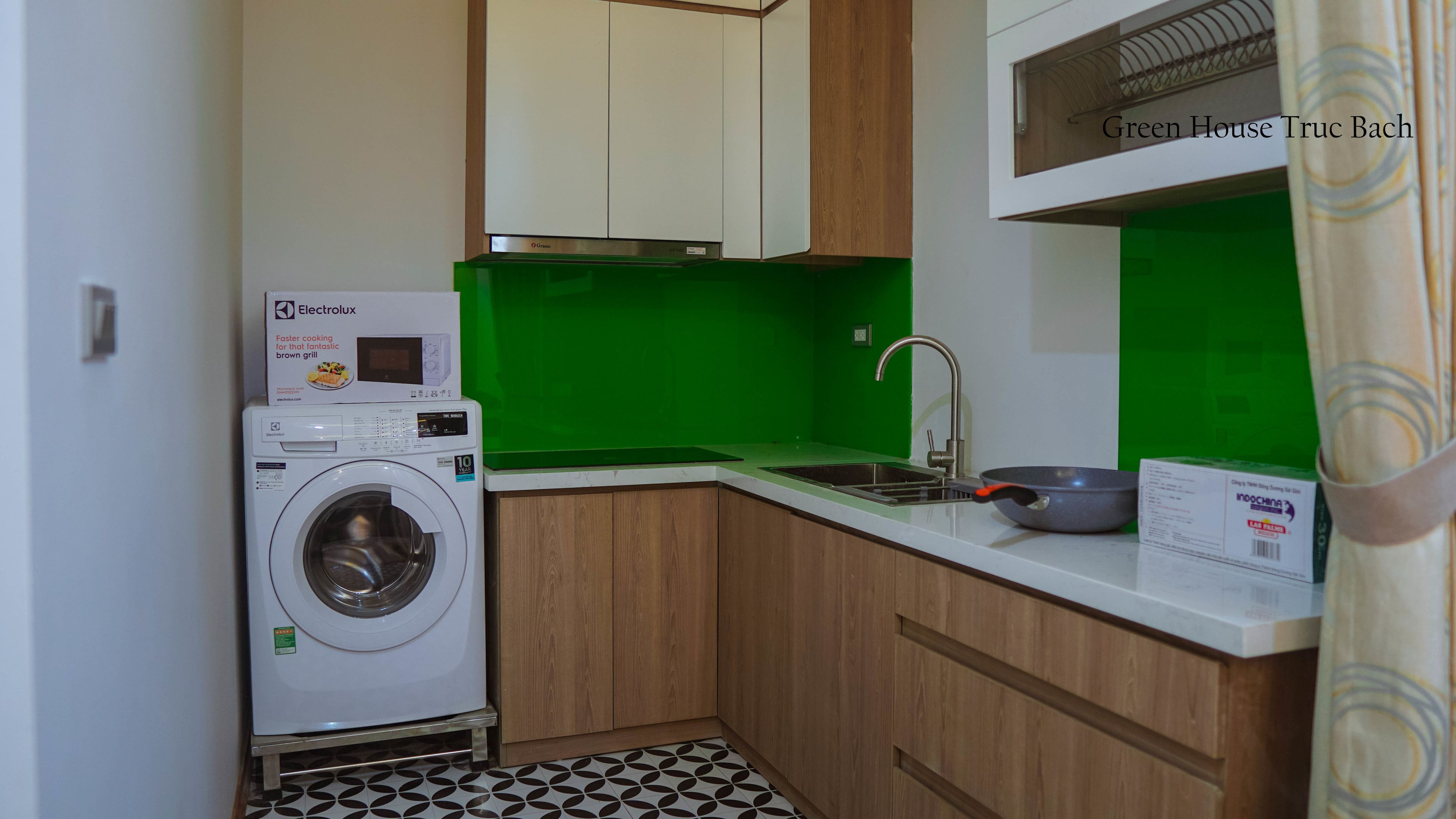 Uma cozinha compacta com máquina de lavar, pia e micro-ondas.