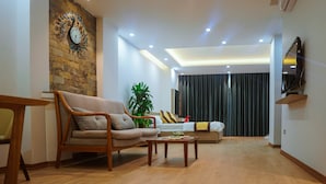 Un saló modern amb un sofà, una taula de centre, un rellotge decoratiu i una televisió penjada a la paret.