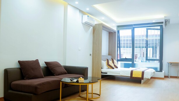 Habitació d'hotel moderna amb un sofà, una taula rodona petita, un llit amb vistes i una finestra gran.