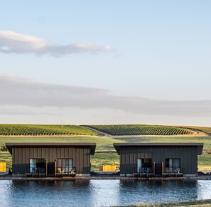 Two modern buildings with balconies overlooking a body of water and a vineyard in the background. - Eritage Resort (Walla Walla)