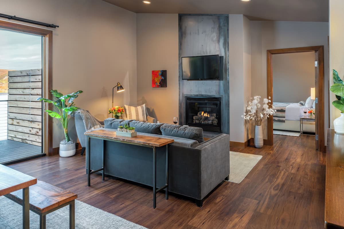 A modern living room with a sofa, a coffee table, a fireplace, and a TV mounted on the wall.