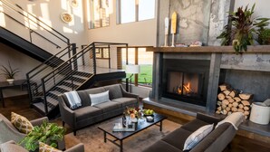 Una sala moderna con chimenea, una escalera y vistas al exterior.