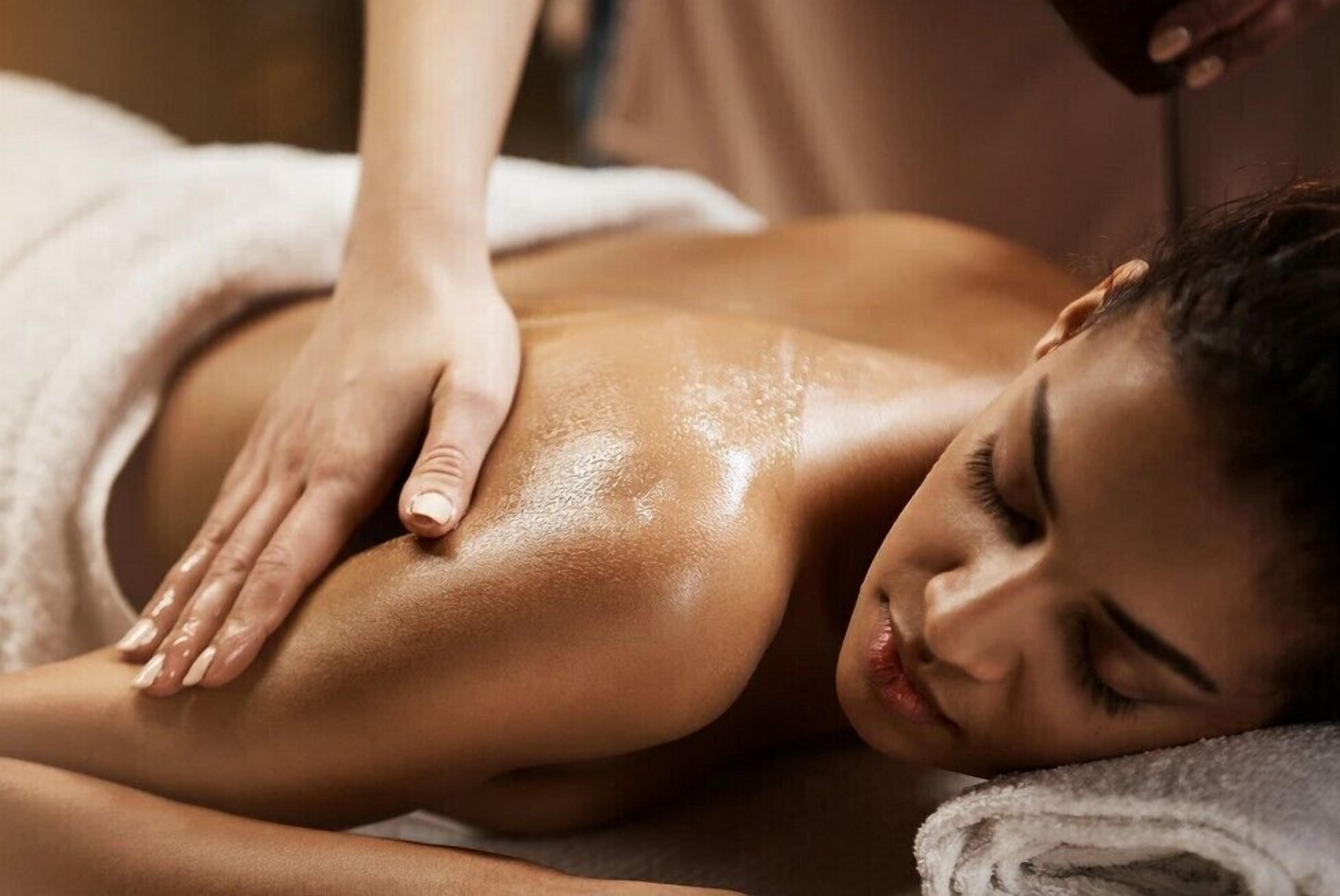 A person receiving a massage in a room with a white towel and a massage table.
