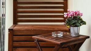 Un banc en bois, une table en métal et une plante en pot.