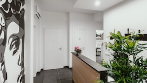 Un hall d'hôtel moderne avec un comptoir d'accueil, un escalier et un panneau indiquant l'emplacement d'un restaurant.