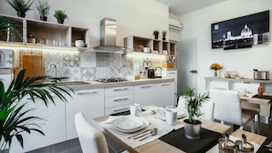 Une cuisine moderne avec des meubles blancs, une cuisinière à gaz et un coin repas avec une table dressée pour deux personnes.