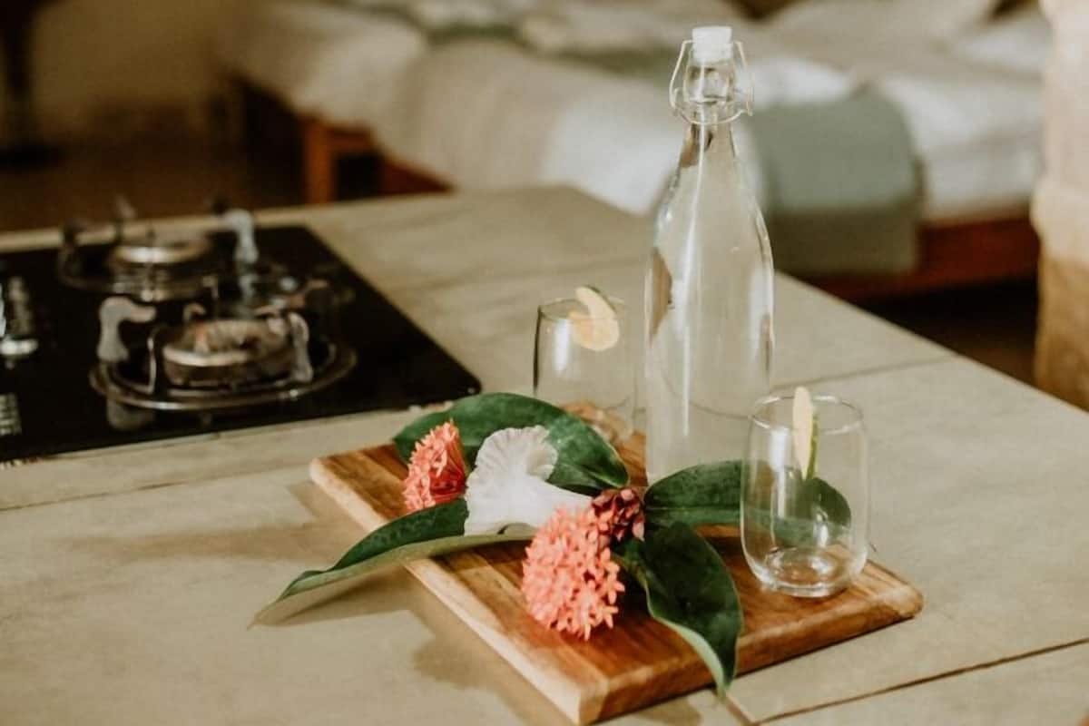 Ein Zimmer mit einem Bett, einem Tisch mit einer Flasche, einer Kerze und Blumen.