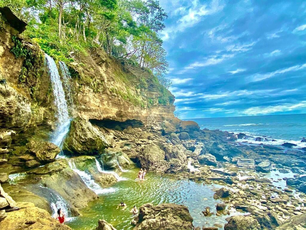 Un paysage naturel comprenant une cascade, un terrain rocheux et une étendue d’eau.