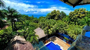 A rooftop pool with a clear view of the ocean, surrounded by lush greenery and palm trees. - Castillo Tambor Resort and Restaurant (Cóbano)