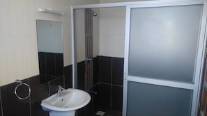 A bathroom with a white sink, a mirror, and a shower enclosure.