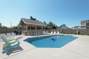 A swimming pool with lounge chairs and a covered seating area.