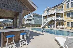 A pool area with a bar, lounge chairs, and a wooden deck.