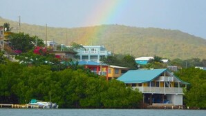 A coastal area with buildings, a dock, and a mountain in the background. - Sea Turtle Studio – Upscale Waterview Retreat, Stunning Sunrises & Full Kitchen! (Culebra)