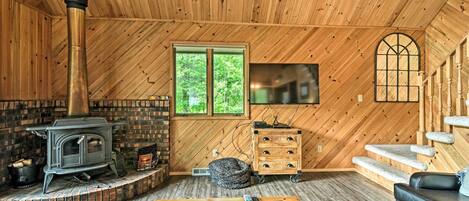 Un intérieur chaleureux avec des éléments en bois, notamment une cheminée, un banc en pierre, une table en bois et un canapé.
