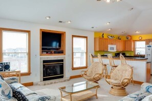 A living room with a fireplace, a television, and a kitchen area with wooden cabinets and a microwave.