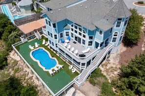 A large, multi-story building with a swimming pool, outdoor seating, and a covered patio area.
