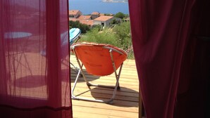 Una habitación con vista al mar, una terraza de madera y una cortina roja.