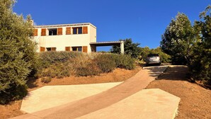 Un edificio moderno con un camino de concreto que lleva a un automóvil estacionado.