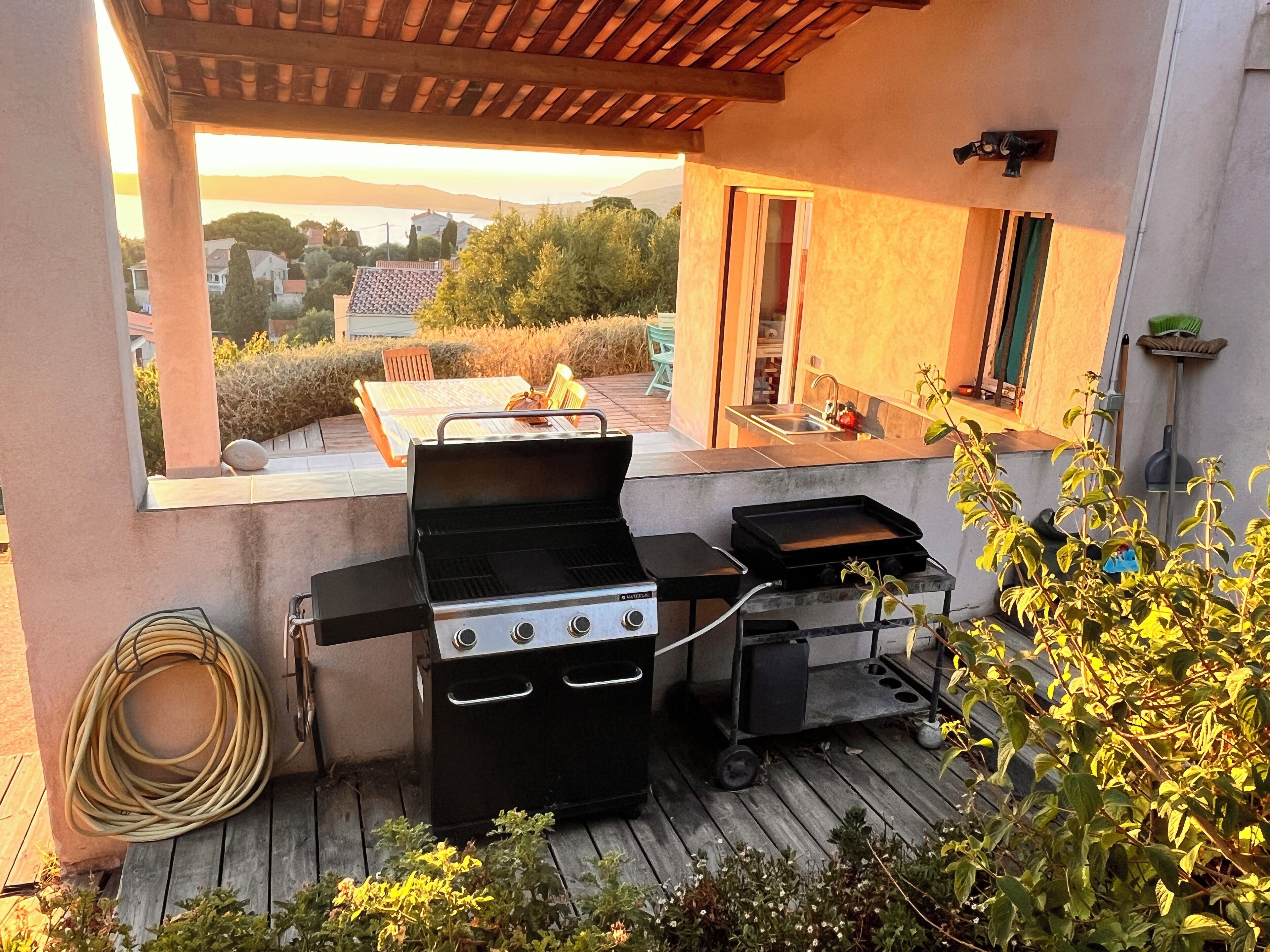 An outdoor patio with a grill, a sink, and a hose.
