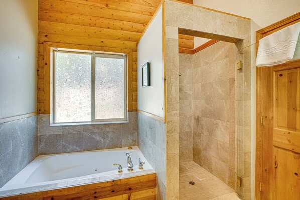 A bathroom with a bathtub, a shower, and a window.