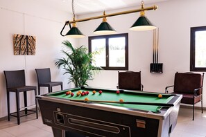 Relax in this stylish space with a SUPERLEAGUE pool table at its center, surrounded by comfortable seating and a touch of greenery.