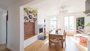 Un vaste espace de vie agrémenté d’une cheminée en briques, d’une table à manger avec des chaises et d’un balcon offrant une vue panoramique.
