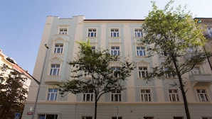 A multi-story building with a light facade and multiple windows.