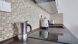 A modern kitchen with a reflective countertop, a kettle, and a toaster.